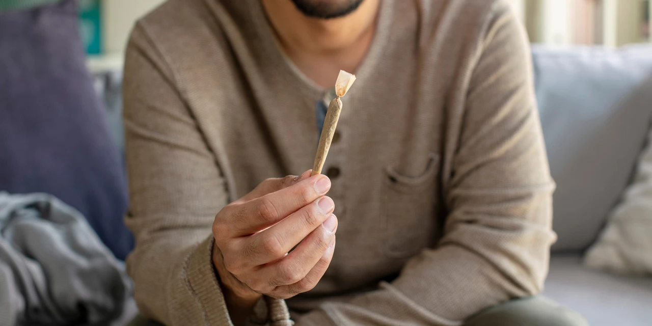 Man houdt een joint vast in zijn hand, passend bij afkicken van wiet en stoppen met blowen.