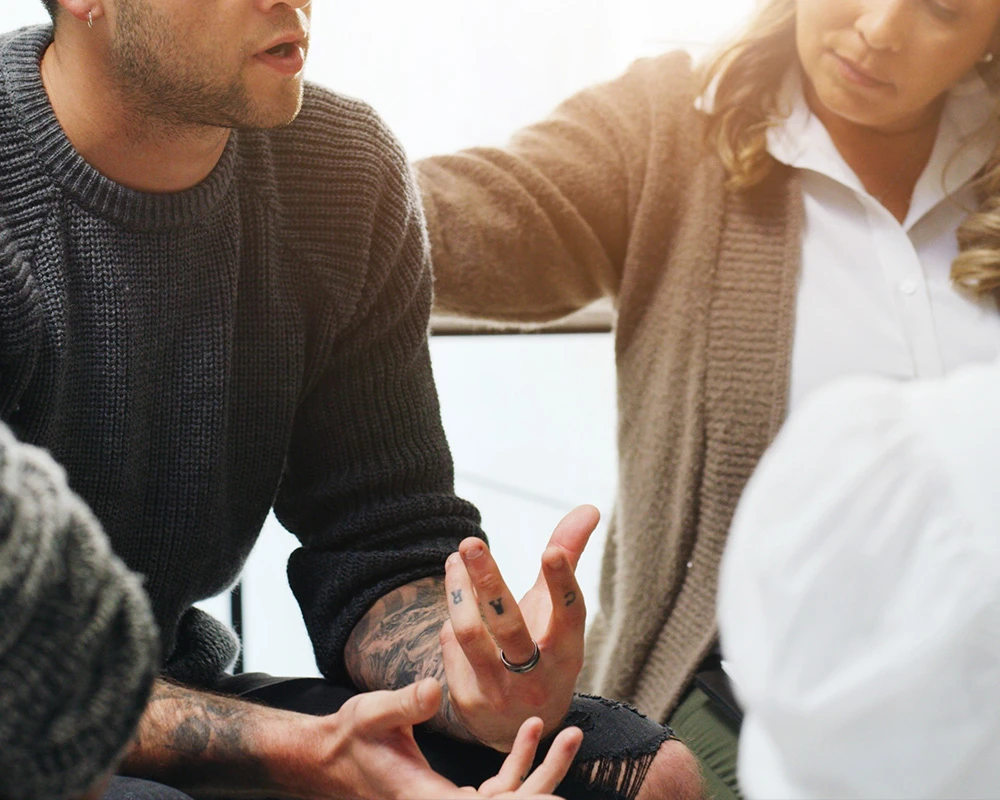 Mensen voeren een open gesprek tijdens een bijeenkomst over herstel en verslaving. De afbeelding past bij begeleiding en ondersteuning tijdens afkicken en duurzaam herstel.
