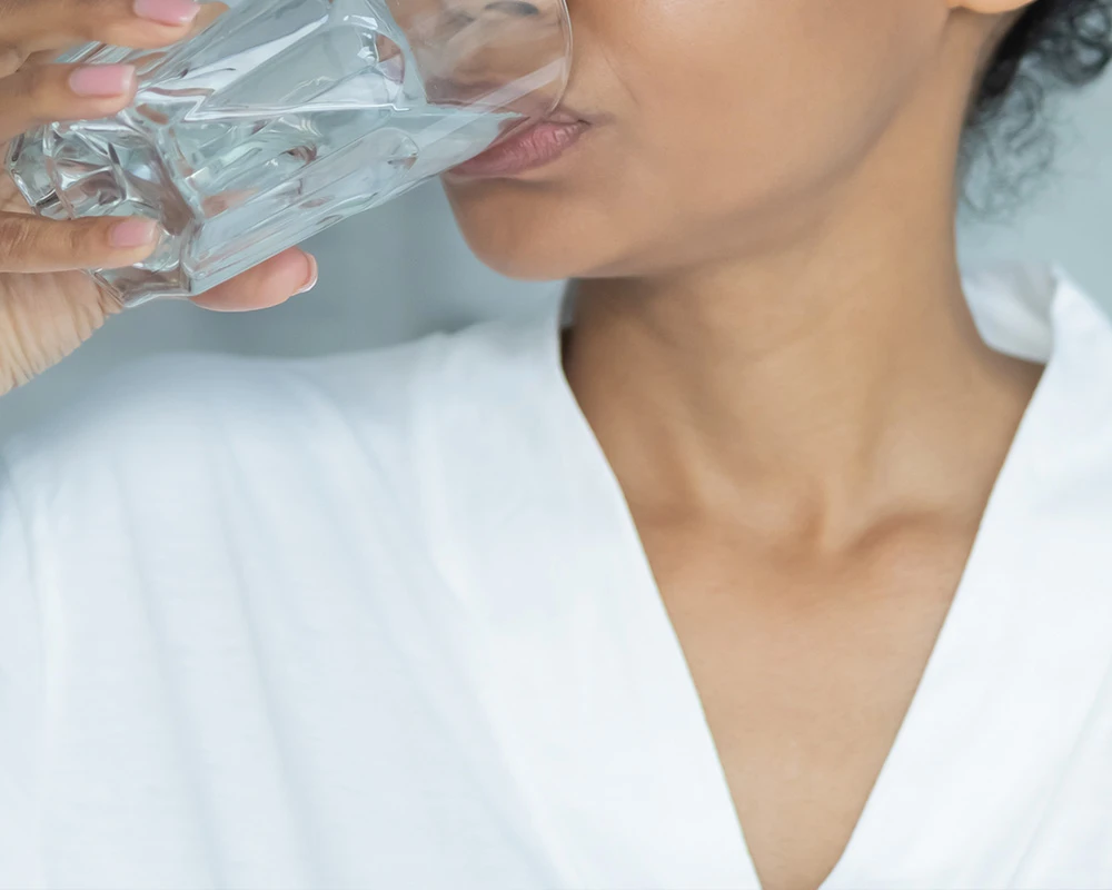 Vrouw drinkt water tijdens een detox om haar lichaam te ondersteunen bij herstel van verslaving.