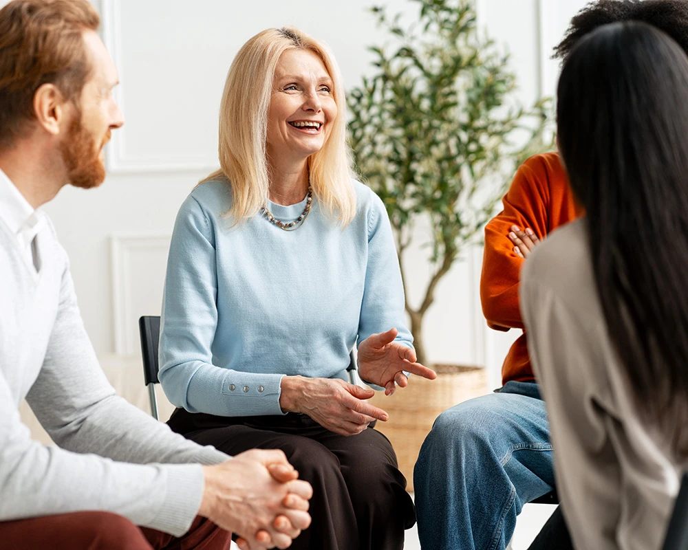 Een groep mensen zit in gesprek tijdens een therapiesessie binnen de verslavingszorg, gericht op ondersteuning en herstel.
