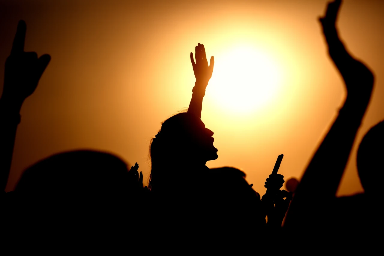 Silhouet-van-vrouw-op-druk-festival Silhouet van vrouw die aan het joelen is tussen andere festivalgangers tegen hoogstaande zon.