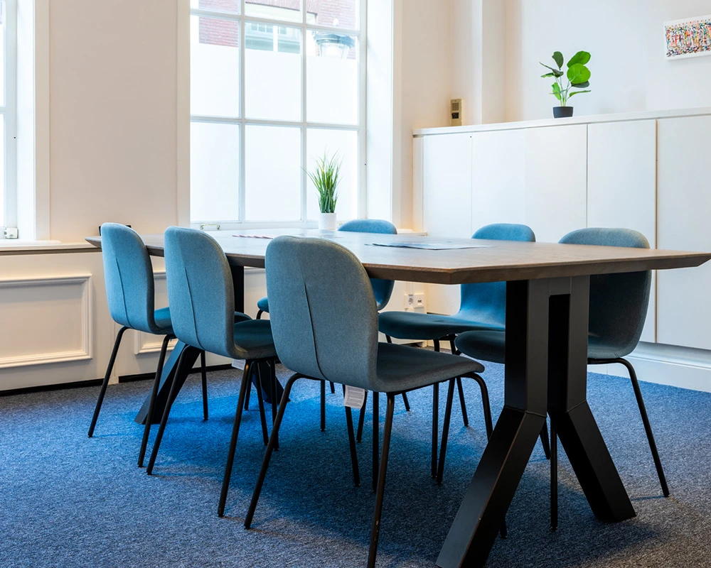 Een moderne vergaderruimte met tafel en stoelen binnen een afkickkliniek in Utrecht.