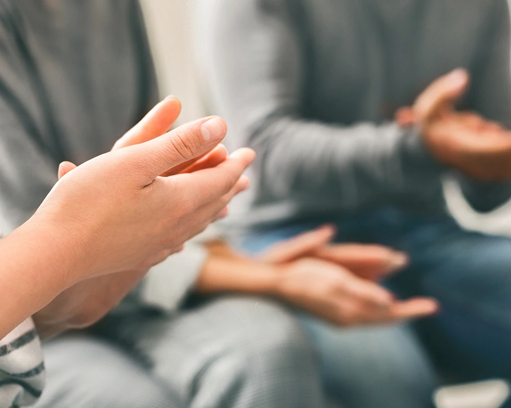 Mensen voeren een open gesprek tijdens een groepssessie binnen de verslavingszorg in een rustige en veilige omgeving.