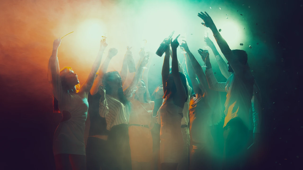 Vrouwen en mannen dansen op een feest met groen-gele discolichten.