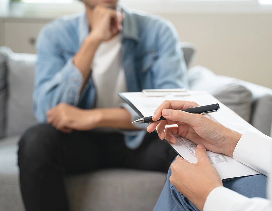 Persoon zit in gesprek met een hulpverlener tijdens begeleiding bij verslavingsproblemen. De afbeelding past bij professionele hulp en ondersteuning bij herstel van een verslaving.