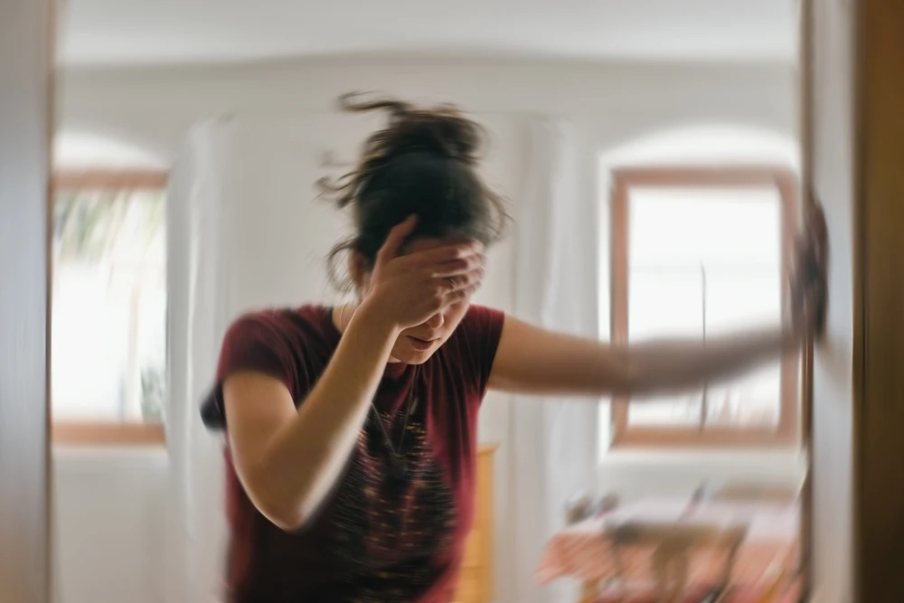 vrouw-is-duizelig-door-bingedrinken Vrouw steunt tegen muur omdat ze duizelig is door bingedrinken.
