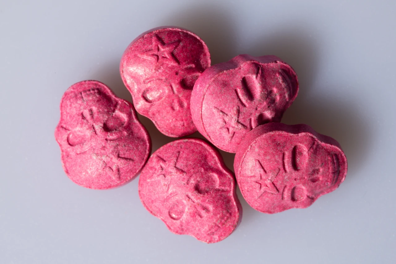 Roze pilletjes in de vorm van doodskopjes die laten zien wat XTC is en hoe deze drug er eventueel uitziet.