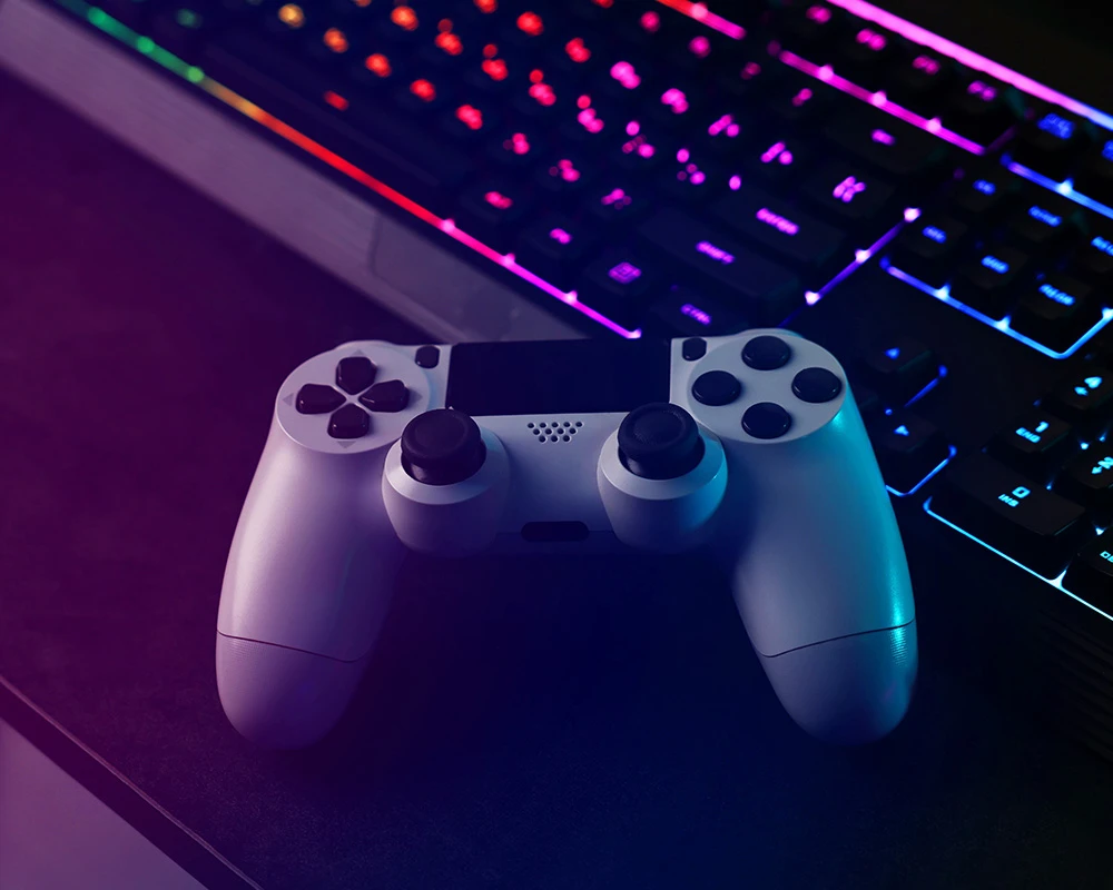 Een gamecontroller ligt voor een verlicht toetsenbord in een donkere gamingruimte. De afbeelding verwijst naar langdurig gamen en gedrag dat kan passen bij verslaafd zijn aan World of Warcraft.