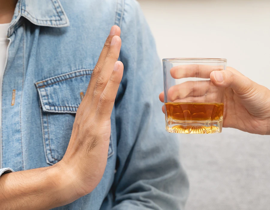 Een persoon weigert een glas alcohol met een afwerend handgebaar, passend bij herstel van alcoholverslaving en gedragsverandering.