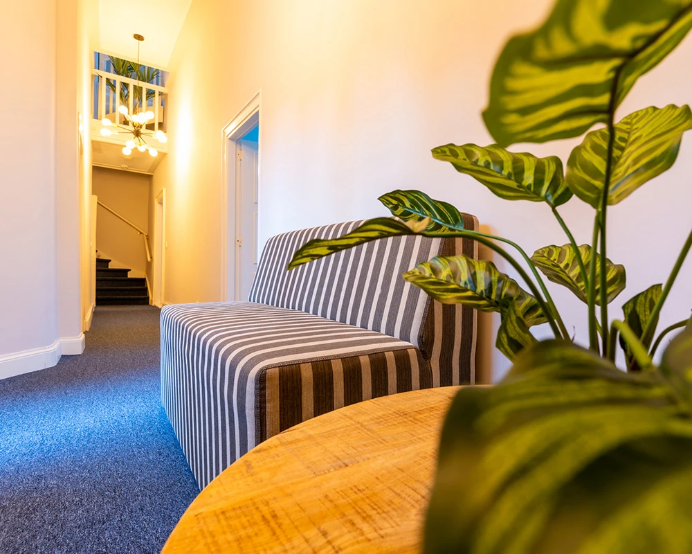 Een sfeervolle hal met zithoek en planten binnen een afkickkliniek in Utrecht.