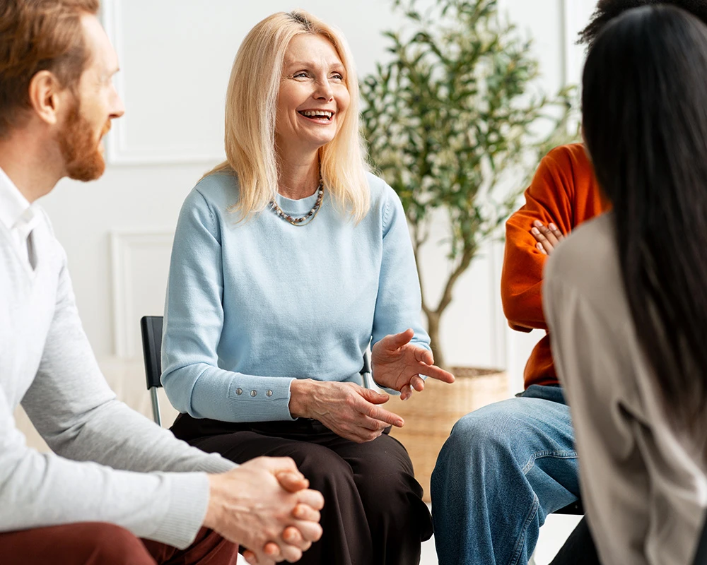 Een groep mensen zit in gesprek tijdens een therapiesessie binnen de verslavingszorg met persoonlijke begeleiding en ondersteuning.