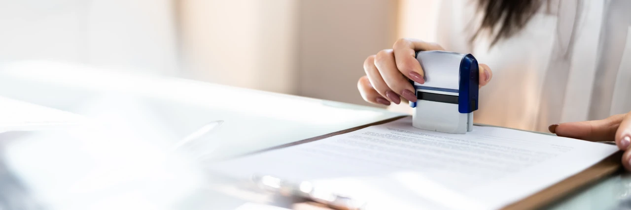 Vrouwenhand-zet-stempel-op-document Vrouwenhand zet stempel op document om kwaliteit te garanderen.