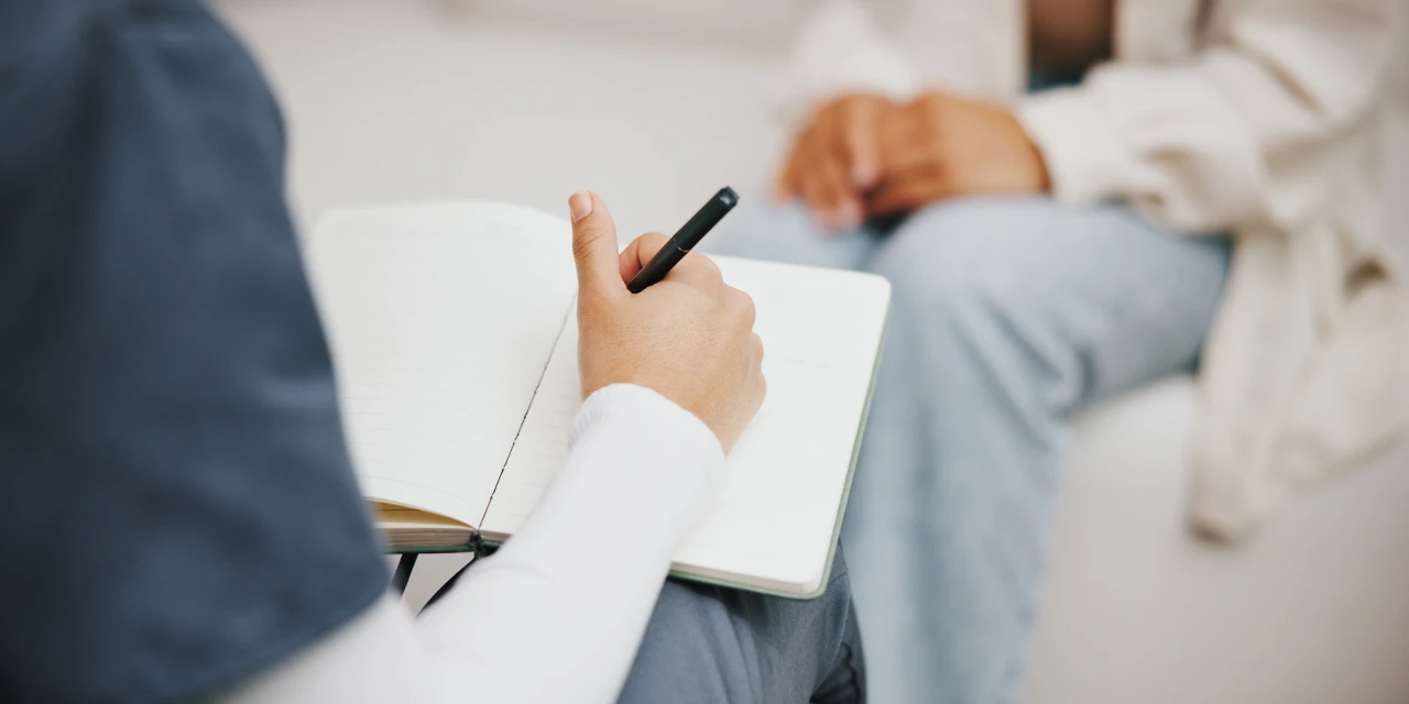 Een behandelaar maakt aantekeningen tijdens een persoonlijk gesprek met een cliënt bij CACN.
