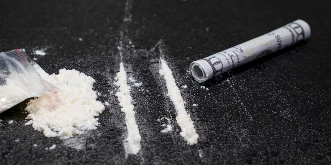 Lijnen cocaïne op tafel met opgerold briefgeld en een zakje cocaïne, passend bij herstellen na coke.