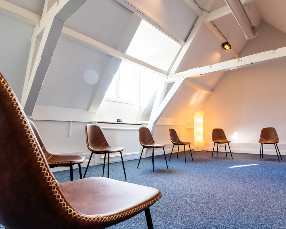 Een lichte groepsruimte met stoelen in een cirkel binnen een afkickkliniek in Utrecht voor gesprekken en behandelingen.