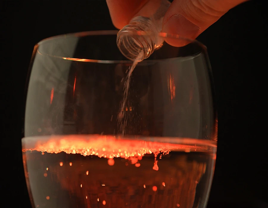 Spiking: poeder wordt in een glas drank gegoten onder rood licht.