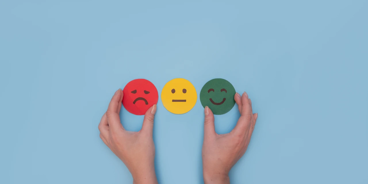 droevige-neutrale-en-blije-emoticon-vastgehouden-door-handen Verdrietige, neutrale en blije emoticon die de diverse emoties uitbeelden die cannabis kan geven.