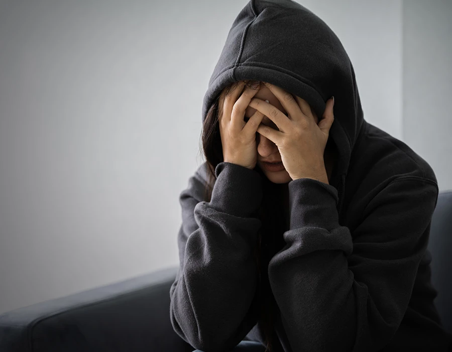 Een persoon zit met handen voor het gezicht tijdens een emotioneel moment door verslaving.