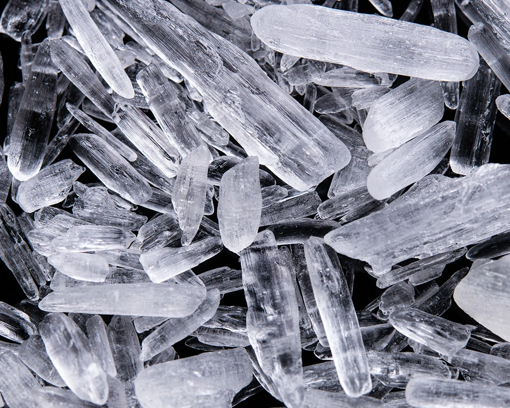 Close-up van transparante pepkristallen op een donkere achtergrond. De afbeelding past bij informatie over drugsgebruik en wat is pep.