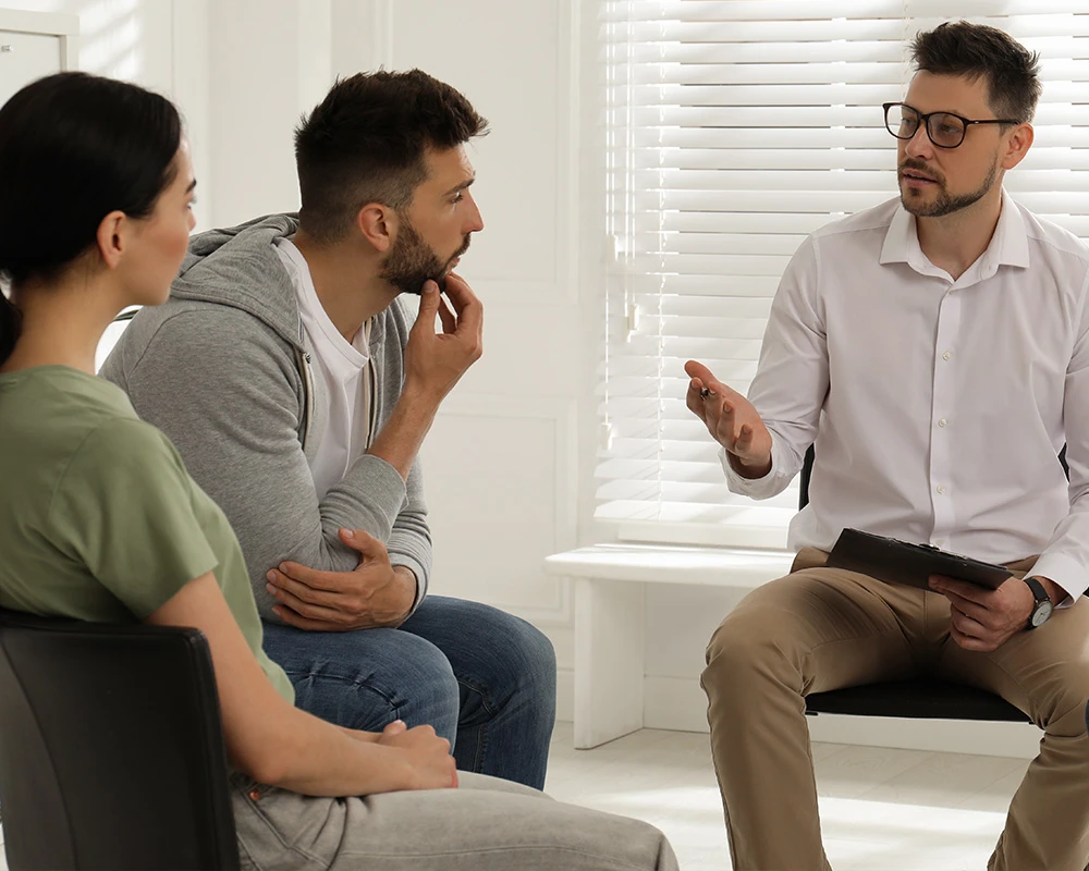 Een therapeut voert een gesprek met twee cliënten tijdens een behandeling binnen de verslavingszorg.