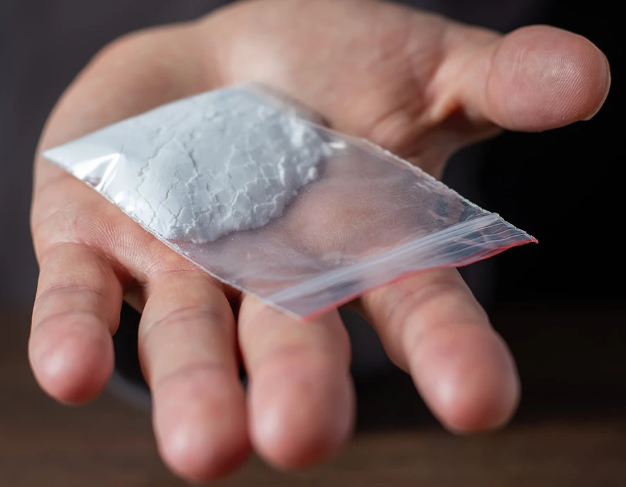 Iemand houdt een zakje coke vast en wilt deze geven.
