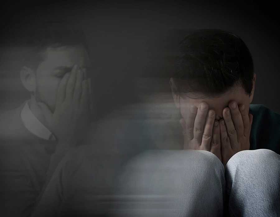 Man zit met zijn handen voor zijn gezicht en oogt emotioneel uitgeput.