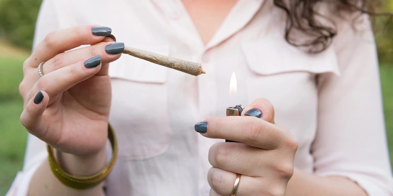 Persoon steekt een joint aan met een aansteker, passend bij symptomen van blowen en cannabisgebruik.