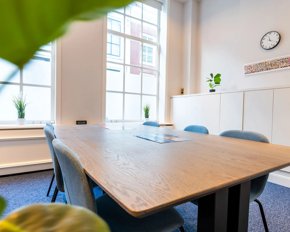 Een lichte ruimte met grote tafel en stoelen binnen een afkickkliniek in Utrecht.