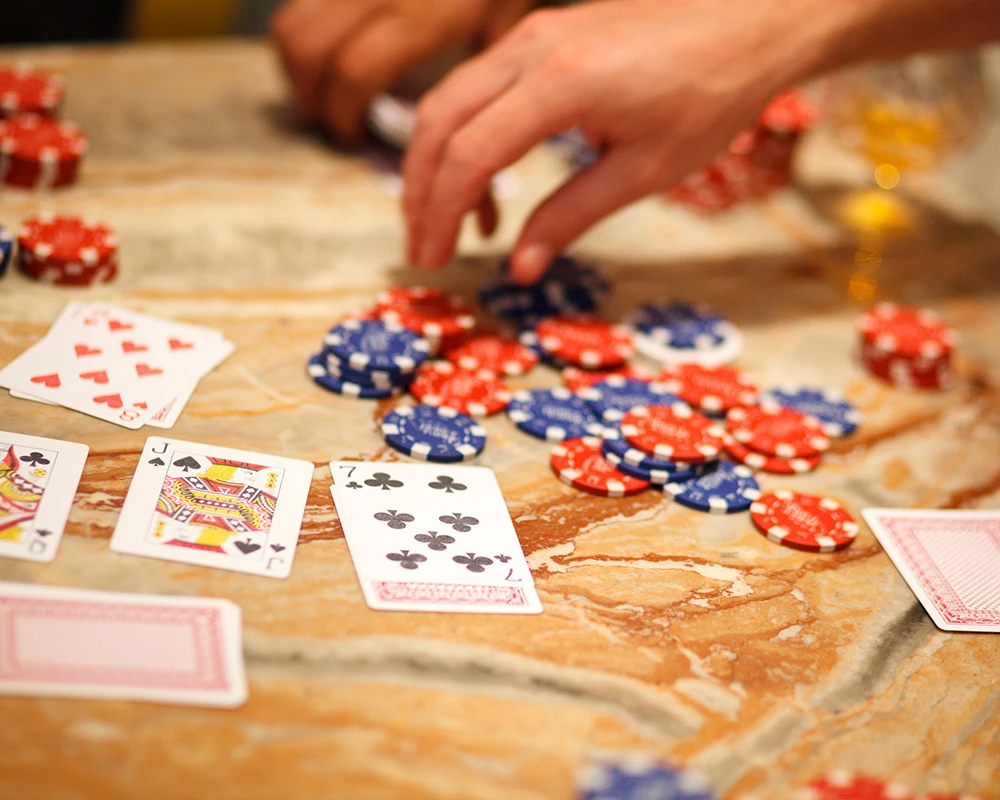 Speelkaarten en gokfiches liggen verspreid op tafel tijdens een gokspel, passend bij gokgedrag en gokverslaving.