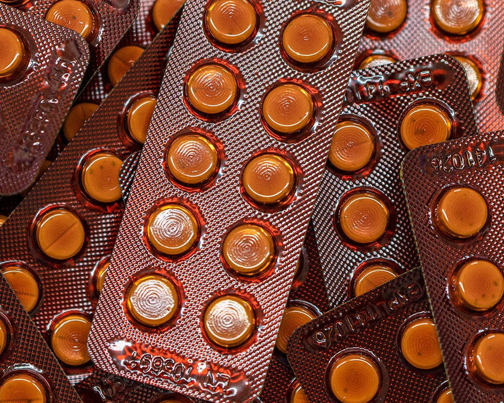 Meerdere blisterverpakkingen met benzodiazepinen tabletten liggen verspreid op elkaar. De afbeelding toont medicatiegebruik en mogelijke risico’s van alcohol en benzodiazepinen.