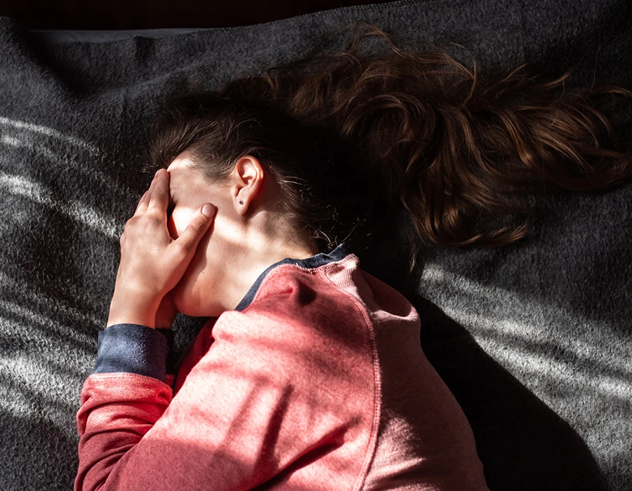 Vrouw ligt met haar hand voor haar gezicht en straalt verdriet en onzekerheid uit.