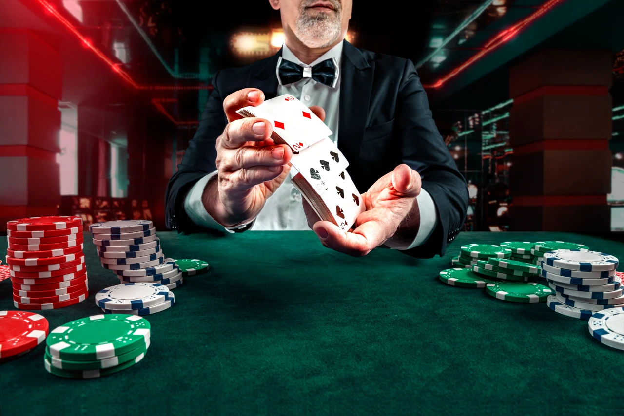 Croupier in casino deelt kaarten aan tafel met fiches en vormt risico voor mensen met gokverslaving.