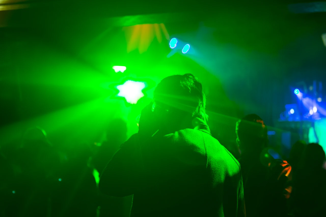 mensen-in-club-met-felgroene-verlichting Mensen in club met felgroene verlichting waar synthetische drugs wordt gebruikt.