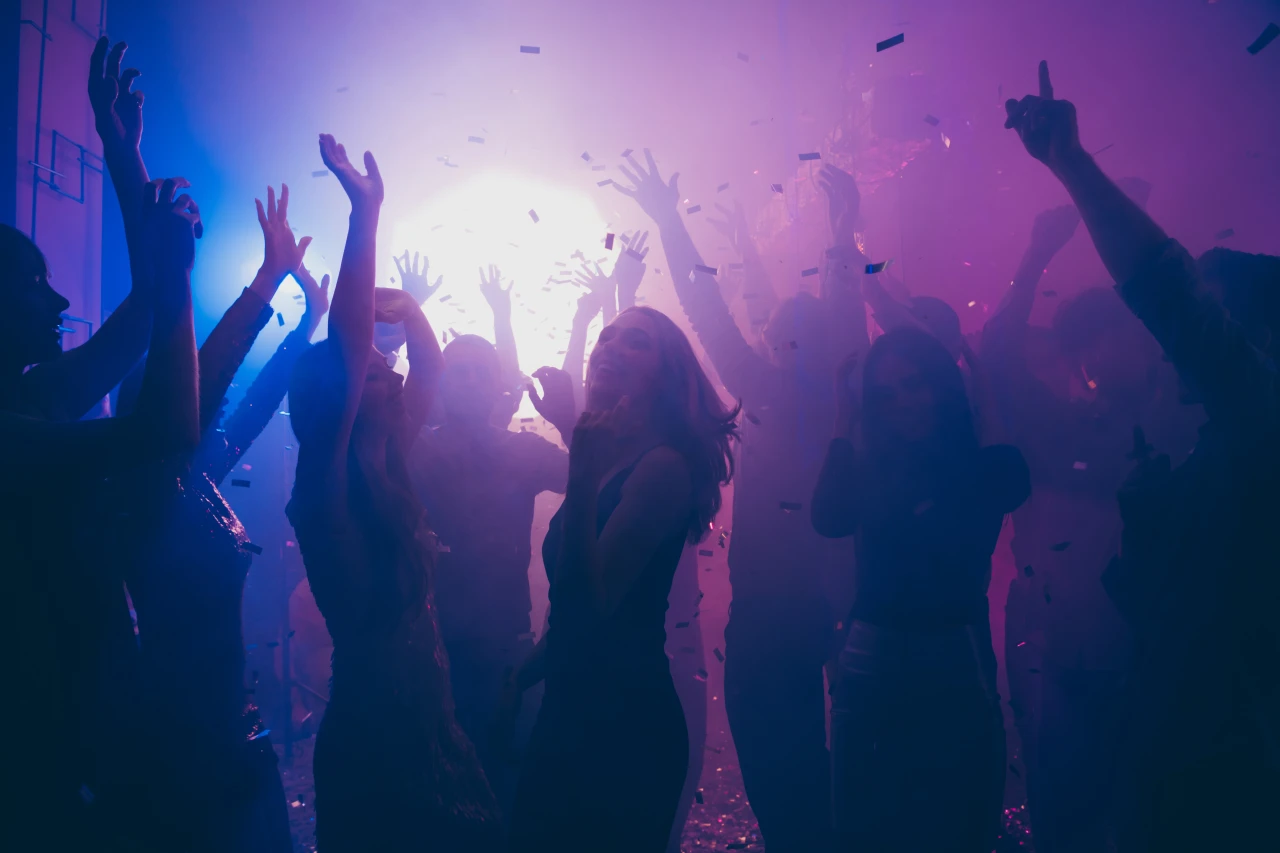 De effecten van MDMA: vrouw danst in een drukke club omringd door mensen en felle lichten.